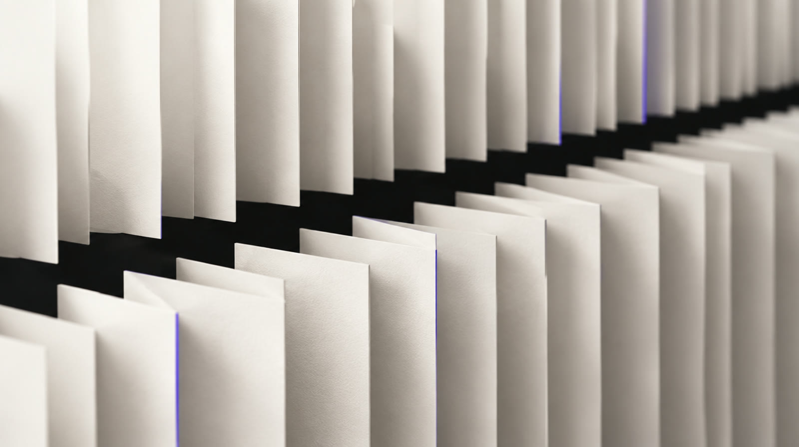 Brand image: sheets of off-white paper in parallel rows over a channel of black ink.
